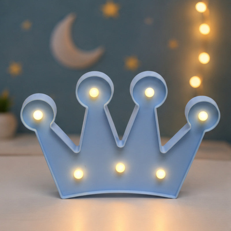 Blue crown-shaped LED night light standing on a wooden surface against a blurred background.